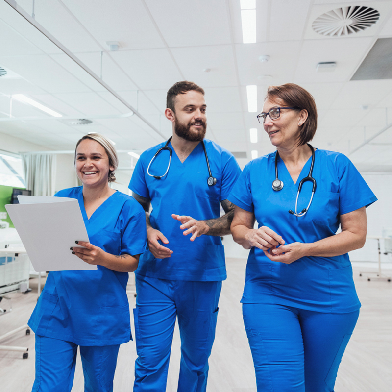 Three nurses walking dressed in blue